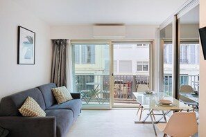 Ein modernes Wohnzimmer mit einer Couch, einem Glastisch und einem Balkon mit Gartenmöbeln.