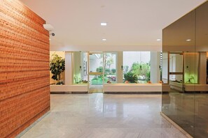Eine geräumige Lobby mit Backsteinwand, einer Glastrennwand und Blick auf einen Garten.