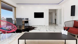 Un salon moderne comprenant un coin repas, un téléviseur à écran plat, un canapé et un fauteuil rouge.