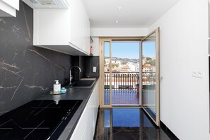 Eine moderne Küche mit schwarzem Marmorfliesenspiegel, einer Edelstahlspüle und Blick auf die Stadt durch eine Glastür.