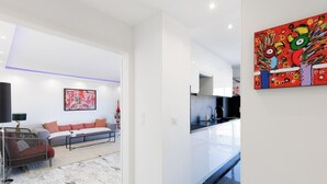 Un salon moderne avec un canapé, un coin repas avec une cuisine, et un couloir.
