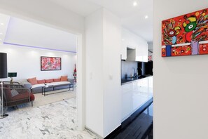 A modern living room with a sofa, a dining area with a kitchen, and a hallway. - Upstays Modern sea view terrace AC (Cannes)