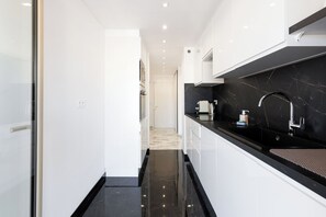 A modern kitchen with a black countertop, white cabinets, and a black marble backsplash. - Upstays Modern sea view terrace AC (Cannes)