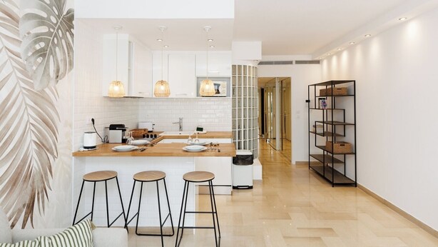 A modern kitchen with white cabinets, a wooden countertop, and a black metal shelving unit. - Upstays Elegant 1BR Gray d'Albion 2min from Palais (Cannes)