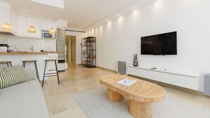 A modern kitchen with white cabinets, a microwave, and a dining area with a bamboo table and bar stools. - Upstays Elegant 1BR Gray d'Albion 2min from Palais (Cannes)