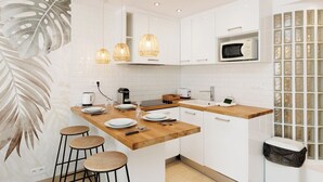 A modern kitchen with white cabinetry, a wooden countertop, and three pendant lights. - Upstays Elegant 1BR Gray d'Albion 2min from Palais (Cannes)