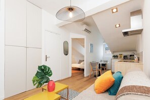 Ein modernes Apartment mit Küche, Essbereich und Wohnzimmer, das ein Sofa und eine Pflanze beinhaltet.