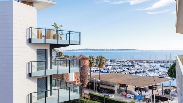 Un edificio moderno con varios balcones que dan a una marina con barcos.