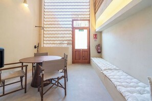 A room with a round wooden table, chairs, a bench, a patterned window, a door with a sign, and a fire extinguisher. - VLC Host - Reina 166 A (Valencia)