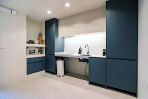 A modern kitchen with dark cabinetry, a white countertop, and a built-in microwave. - VLC Host - Reina 166 A (Valencia)