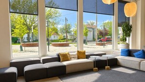 A modern living room with large windows, a sectional sofa, and a potted plant. - Bay View Designer 2BR · Best Location with Balcony, Gym, and Terrace · Sleeps 6 (Milwaukee)