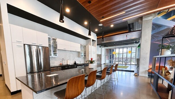A modern kitchen with a central island, stainless steel appliances, and bar stools. - Bay View Designer 2BR · Best Location with Balcony, Gym, and Terrace · Sleeps 6 (Milwaukee)