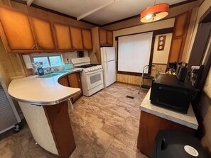A compact kitchen with wooden cabinets, a white stove, a sink, and a black refrigerator.
