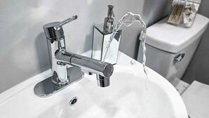 Een wastafel met een chromen kraan en een zeepdispenser.