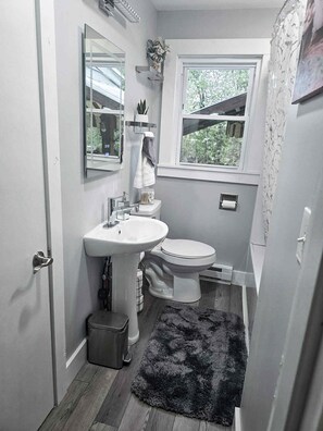 Un baño pequeño con lavamanos, inodoro y una ventana.