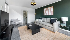 Ett modernt vardagsrum med en soffa, ett soffbord, en tv och en tavla på väggen.