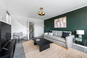 Ein modernes Wohnzimmer mit Sofa, Couchtisch, Fernseher und einem Bild an der Wand.