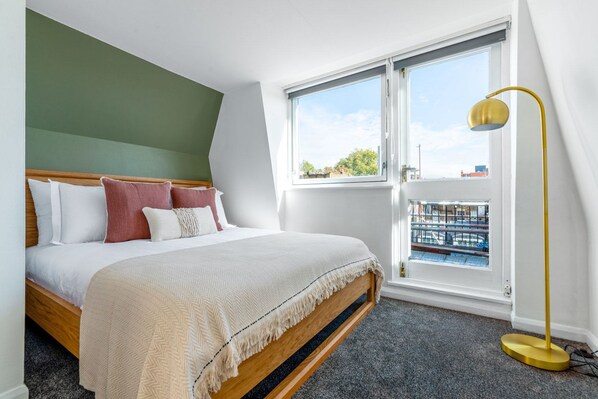 Un dormitorio con cama, ventana y lámpara de pie.