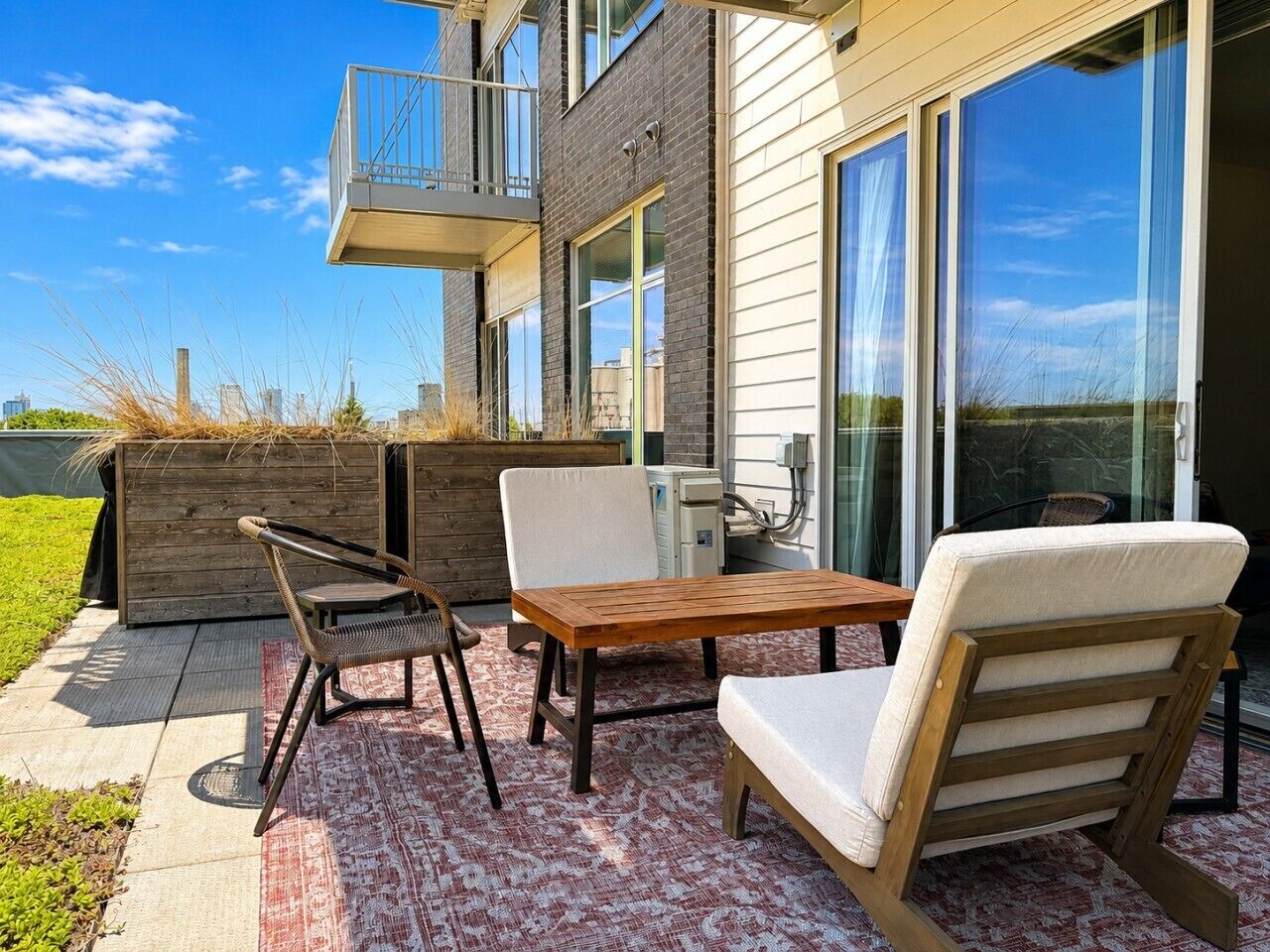 Un patio moderno al aire libre con una mesa y sillas de madera, un banco integrado y vistas del horizonte de la ciudad.