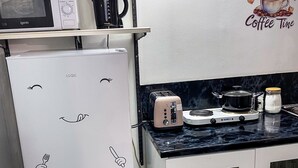A kitchen with a white refrigerator, a toaster, a kettle, and a coffee machine on the counter. - Large StudioFlat in heart of Camden market (London)