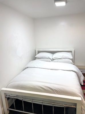 A single bed with white bedding in a room with plain white walls and a visible radiator. - Large StudioFlat in heart of Camden market (London)