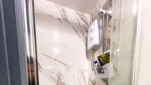 A bathroom with marble walls, a glass shower enclosure, and a soap dispenser mounted on the wall. - Large StudioFlat in heart of Camden market (London)