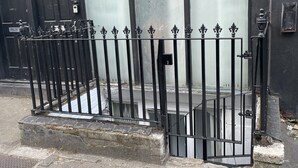 A black metal gate with a fire exit sign, a door with a number, and a window with frosted glass. - Large StudioFlat in heart of Camden market (London)