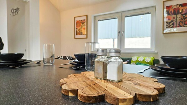A kitchen counter with salt and pepper shakers, a glass, and black plates.