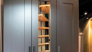 Ein Kleiderschrank mit einer zentralen, durchsichtigen Luke, die eine Holzleiter zeigt.