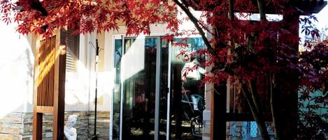 A patio with stone flooring, a statue, and a glass door leading to a covered area.