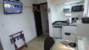 A compact hotel room with a kitchenette, a TV mounted on the wall, a desk with a computer, and a chair. - Private  1-bedroom studio/efficiency safest location in Panama City: Walk to all (Panamá)