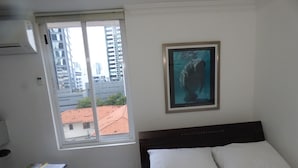 A bedroom with a bed, a desk with a chair, a window, and a framed picture on the wall. - Private  1-bedroom studio/efficiency safest location in Panama City: Walk to all (Panamá)