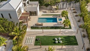 Una casa moderna con piscina, mobiliario exterior y un césped cuidado.