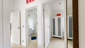 A hallway with white doors leading to a bathroom and a wardrobe.
