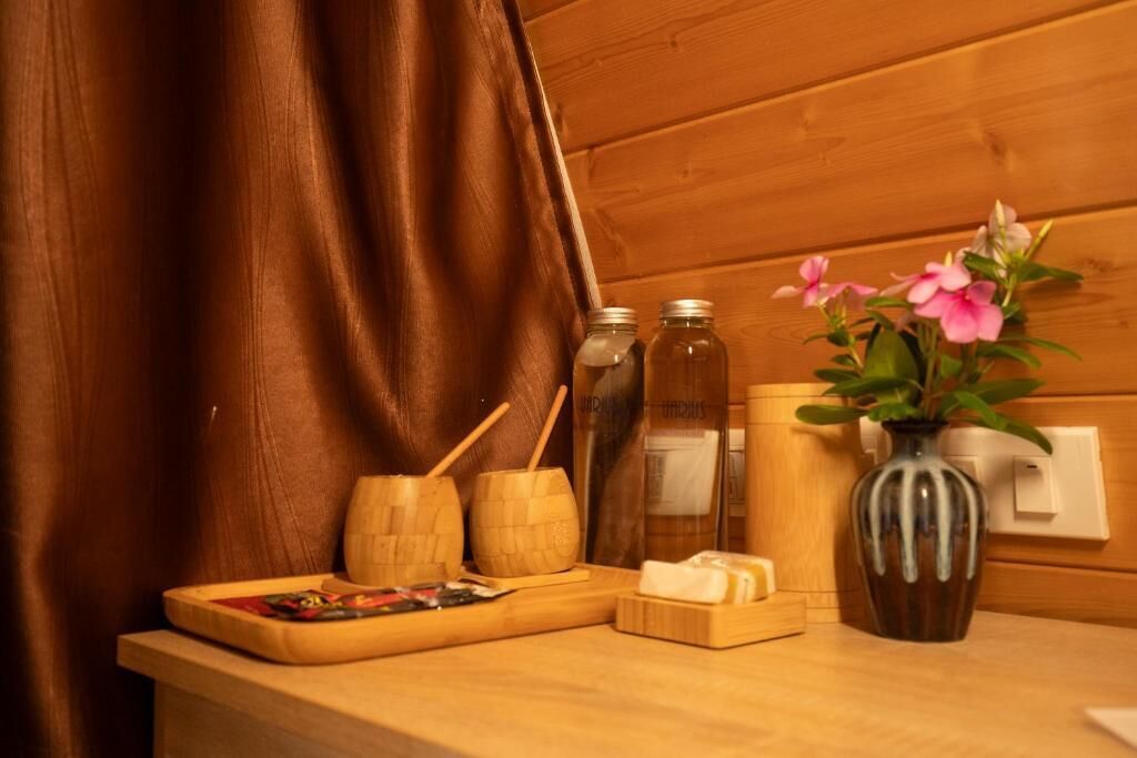 A wooden table with a tray, wooden bowls, a vase with flowers, and bottles.