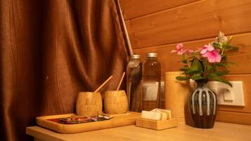 A wooden table with a tray, wooden bowls, a vase with flowers, and bottles.