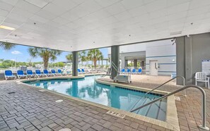 Un espace piscine équipé de chaises longues, d’un escalier pour piscine et d’un panneau indiquant une zone peu profonde.