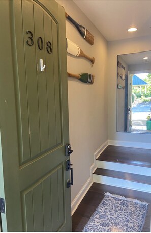 Una puerta verde con el número 308, una decoración de pared con un remo de madera, una escalera con detalles blancos y una alfombra estampada.