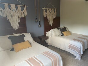Two beds with macrame wall hangings, a nightstand, and a hanging light fixture. - Aura Jungle Oasis (Tulum)