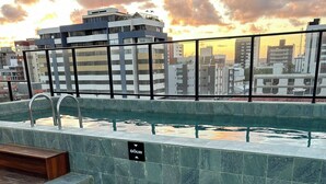 A rooftop pool with clear water, a 60cm depth sign, and a cityscape view in the background. - Melhores Flats - Exclusividade vista mar (Cabedelo)