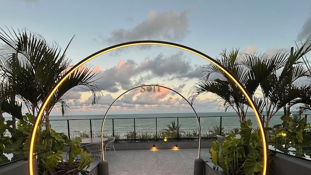An outdoor pathway with a curved archway, leading to a view of the ocean. - Melhores Flats - Exclusividade vista mar (Cabedelo)