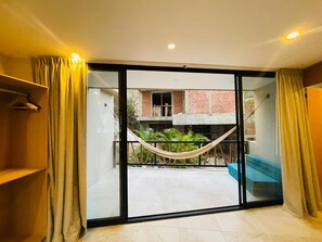 Ein Zimmer mit einer Schiebetür zum Balkon, auf dem eine Hängematte steht.