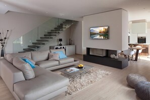 Ein modernes Wohnzimmer mit Sofa, Couchtisch, Kamin und Treppe.