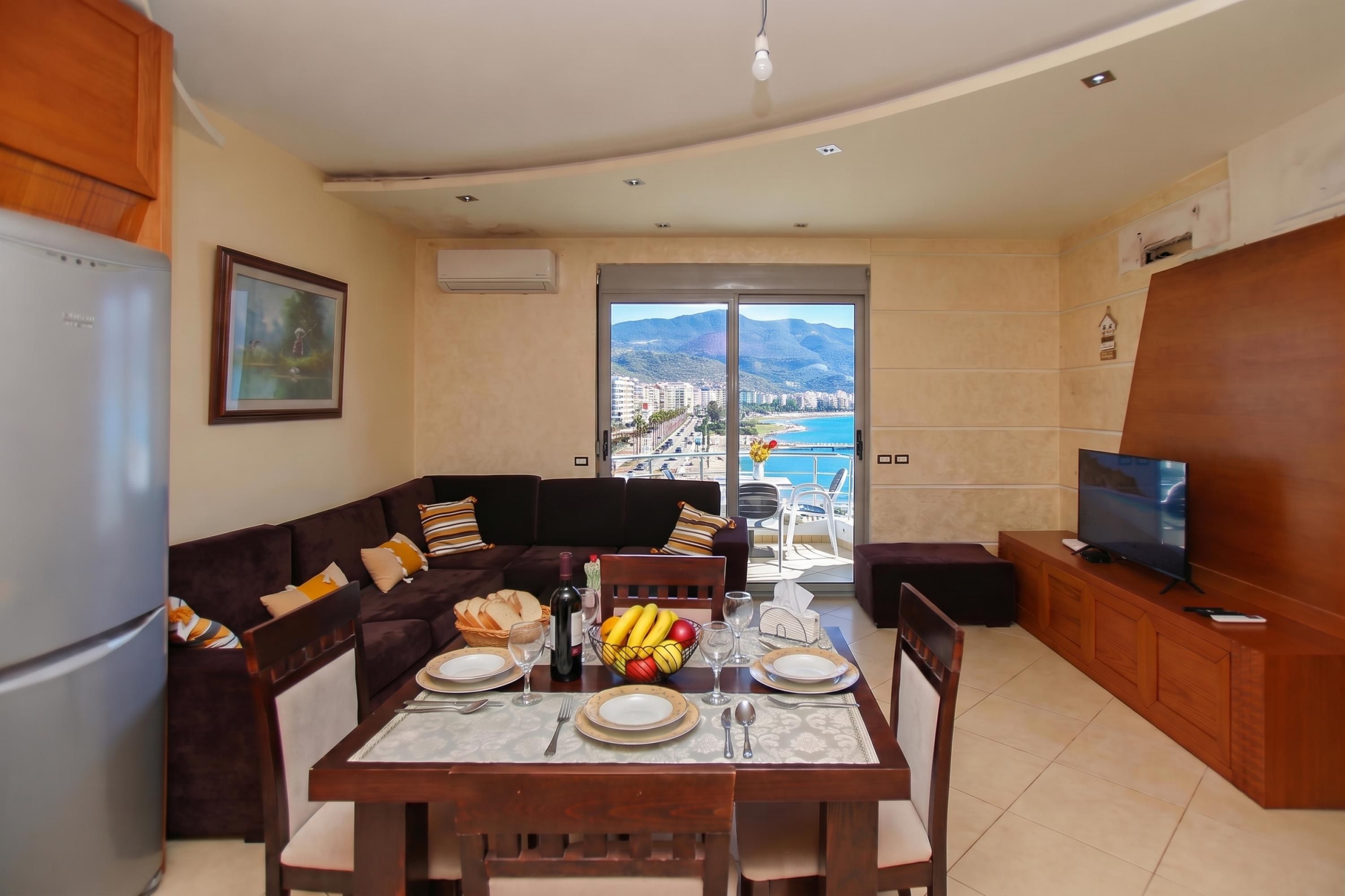 A modern living room with a dining area, a television, and a balcony with a city view.