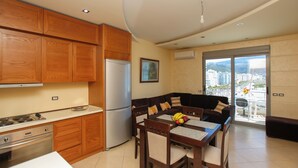 A modern kitchen with wooden cabinets, a refrigerator, and a dining area with a table and chairs. - Holiday Apartment Central & Sea View, Vlore, Albania (Vlore)