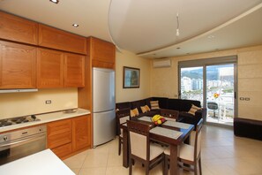 A modern kitchen with wooden cabinets, a refrigerator, and a dining area with a table and chairs. - Holiday Apartment Central & Sea View, Vlore, Albania (Vlore)