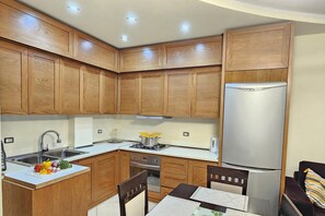 Eine Küche mit Holzausstattung, einem Edelstahlkühlschrank, einer Spüle und einem Essbereich mit Stühlen und einem Tisch.