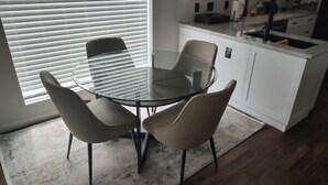 A modern kitchen with a glass dining table and chairs, a white countertop, and a window with blinds. - Completely Remodeled, Perfect for the World Cup (Dallas)