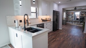 A modern kitchen with white cabinetry, a black refrigerator, and a built-in island with a sink. - Completely Remodeled, Perfect for the World Cup (Dallas)