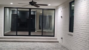 A room with a ceiling fan, a sliding glass door leading to a bathroom, and a tiled floor. - Completely Remodeled, Perfect for the World Cup (Dallas)